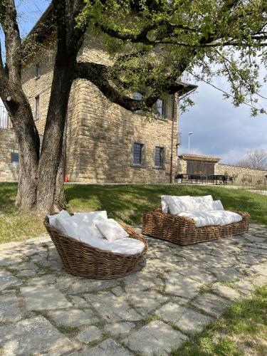 two wicker chairs sitting on a patio under a tree at Foresteria Antica Bastia B&B in Bergamo