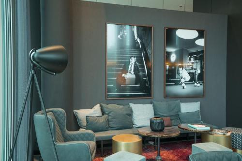 a living room with a couch and two pictures at Motel One Berlin-Upper West in Berlin