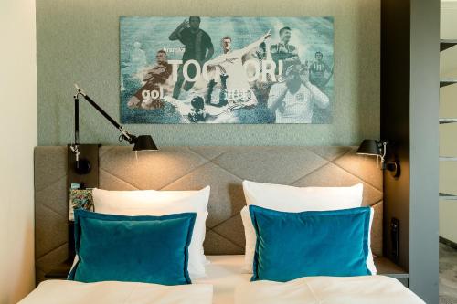 a hotel room with a bed with blue pillows at Motel One München-Garching in Garching bei München
