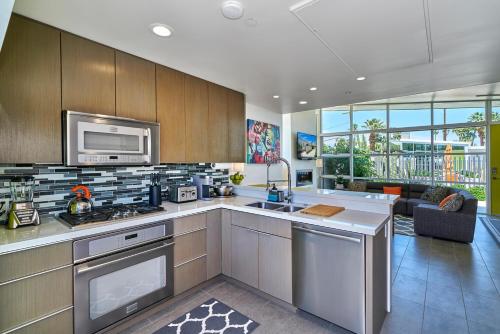 a kitchen with stainless steel appliances and a living room at Sophia Oasis Luxe 2BR Condo with Mountain Views in Palm Springs