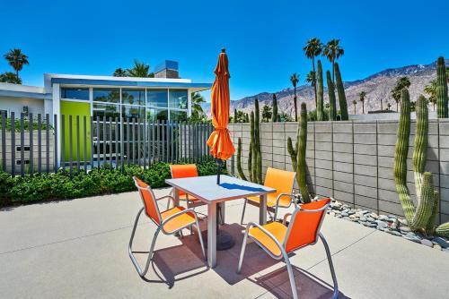 a table with chairs and an umbrella in front of a house at Sophia Oasis Luxe 2BR Condo with Mountain Views in Palm Springs