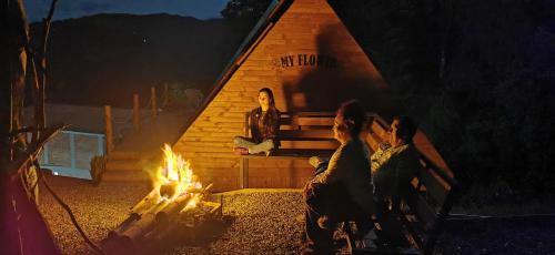 un grupo de personas sentadas alrededor de un fuego en una cabaña en Glamping Villa Gilma en Sevilla