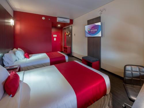 a hotel room with two beds and a tv at Ramada Encore by Wyndham Guadalajara Sur in Guadalajara