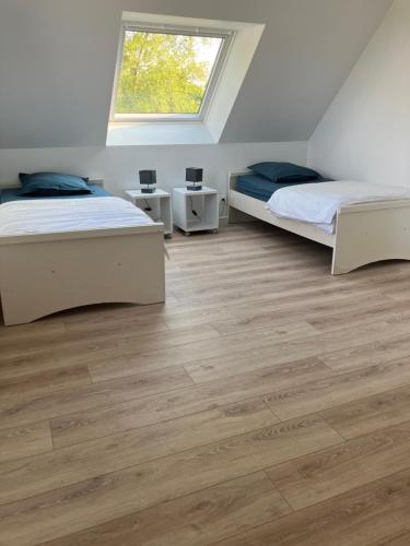 2 camas en una habitación con suelo de madera en Bien être à la campagne, en Le Mesnil-Amand