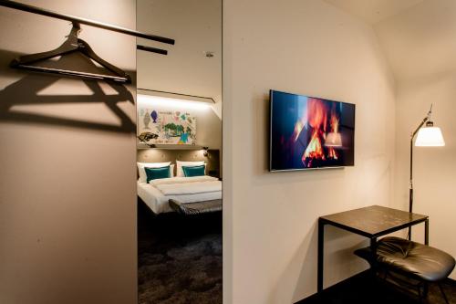 a room with a bed and a television on a wall at Motel One München-Haidhausen in Munich