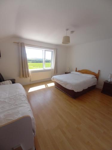 a bedroom with two beds and a large window at Teach na Coille B&B in Midleton