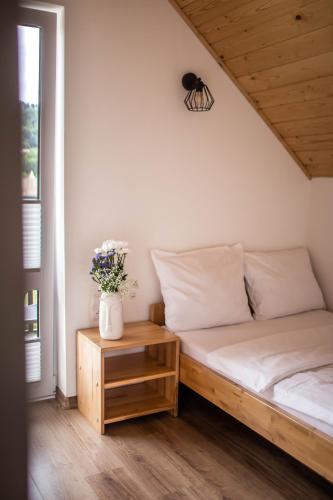 a bedroom with a bed and a table with flowers at Domki Lux Gródek nad Dunajcem in Gródek Nad Dunajcem