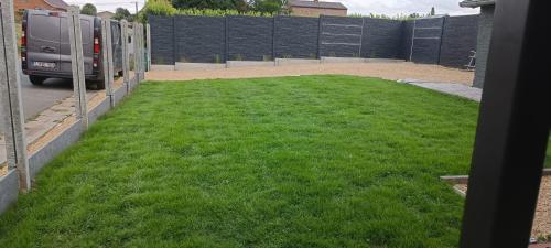 a yard of green grass with a fence and a truck at Les roses d'Olga in Aubechies
