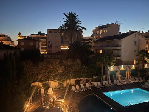 - une vue sur une piscine avec des chaises et un bâtiment dans l'établissement Croisette Martinez, terrasse, à Cannes