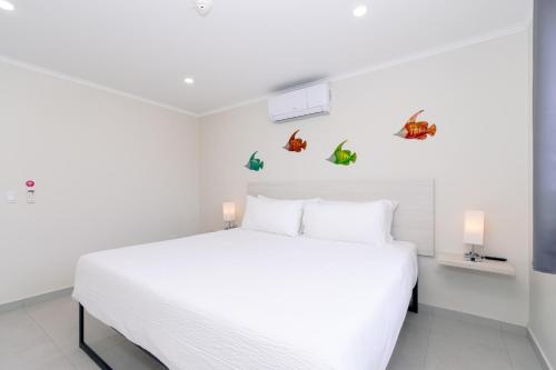 Dormitorio blanco con cama blanca con mariposas en la pared en Summerside 4 Rooi Santo 10-A, en Palm-Eagle Beach