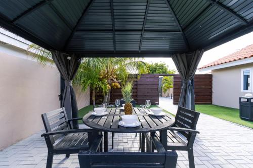 a table and chairs under a black patio umbrella at Solito 52 in Oranjestad