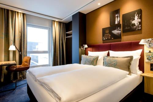 un grande letto bianco in una stanza con una finestra di Motel One Stuttgart-Mitte a Stoccarda