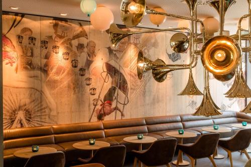 a restaurant with tables and a leather couch at Motel One München-Westend in Munich