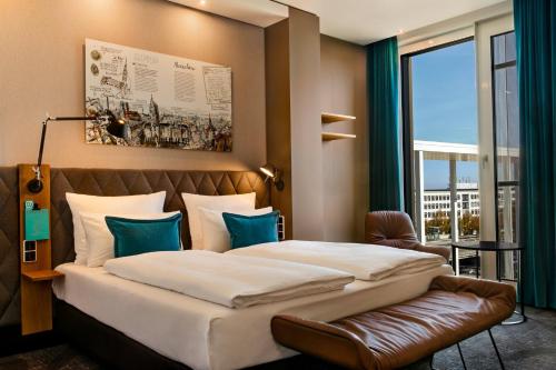a bedroom with a large bed and a large window at Motel One München-Messe in Munich