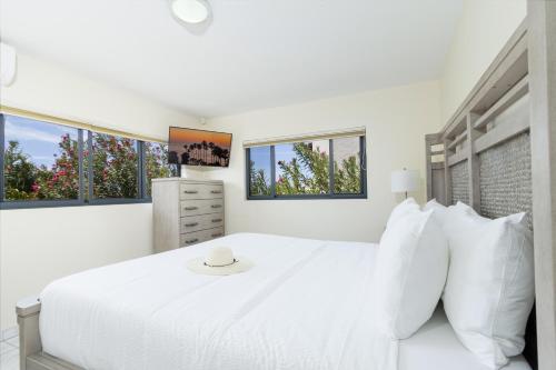 a white bedroom with a white bed and windows at Koyari 36-F in Palm-Eagle Beach