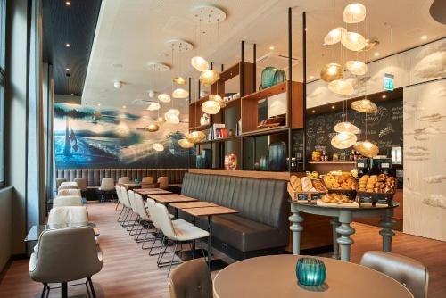 a restaurant with tables and chairs and chandeliers at Motel One Zürich in Zürich