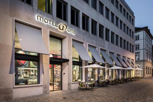 a store front of a building with tables and umbrellas at Motel One Basel in Basel