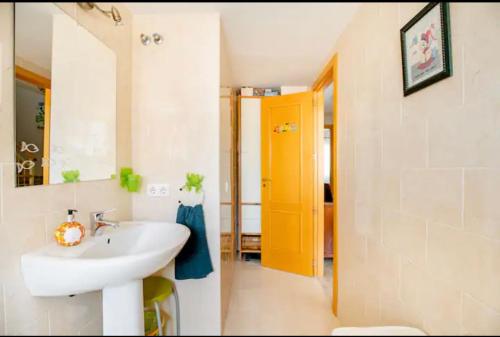 uma casa de banho com um lavatório branco e uma porta amarela em La casa de Marilo em Tomares