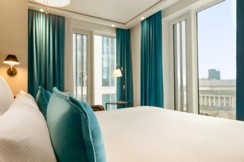1 dormitorio con 1 cama con cortinas y ventanas azules en Motel One Manchester-St. Peter´s Square en Mánchester