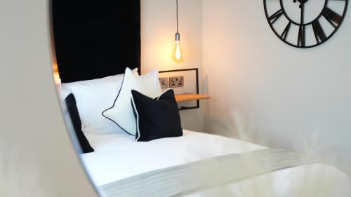 a bed with black and white pillows and a clock at Five Apartments in Blackpool