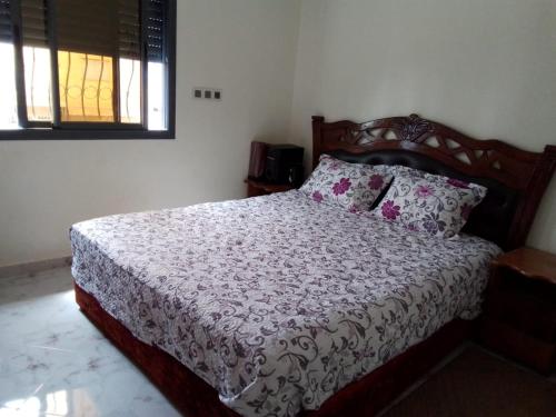 a bedroom with a bed with a wooden headboard at إقامة أحمد 1 in Agadir