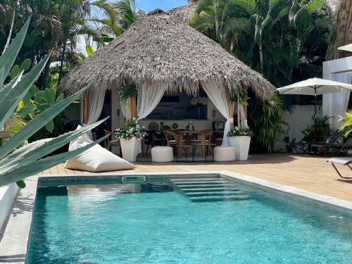 a resort with a swimming pool and a thatch umbrella at Leeloo Boutique Hotel in Las Terrenas