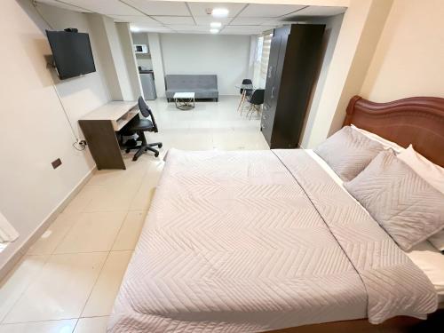 Cama grande en habitación con escritorio y ordenador en Hostal Posada Del Sol, en Guayaquil