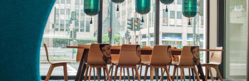 a dining room table with chairs and a large window at Motel One Düsseldorf Hauptbahnhof in Düsseldorf