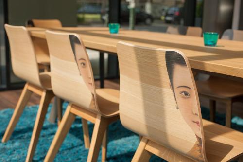 a row of wooden chairs sitting at a wooden table at Motel One Düsseldorf Hauptbahnhof in Düsseldorf