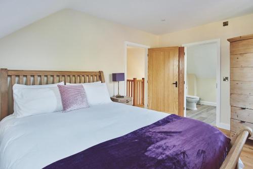 a bedroom with a large bed and a bathroom at The Byre 