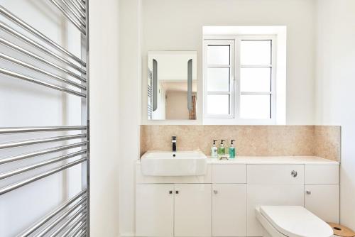a white bathroom with a sink and a mirror at Steward's Cottage 