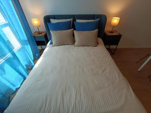 a large white bed with blue curtains and two lamps at Studio Cosy neuf + lit bébé à 4 minutes RER A in Montévrain