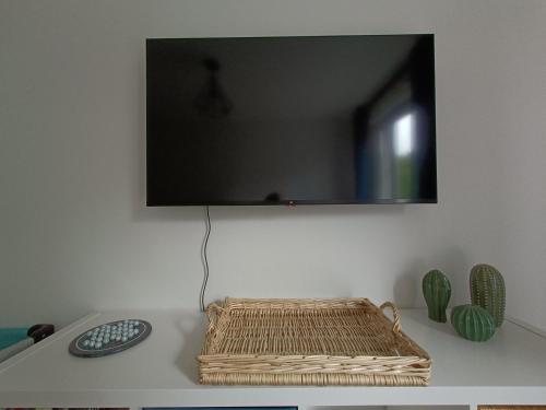 a television on a wall with a wicker basket on a table at Studio Cosy neuf + lit bébé à 4 minutes RER A in Montévrain
