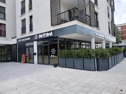 a store front of a building with plants in front at Studio Cosy neuf + lit bébé à 4 minutes RER A in Montévrain