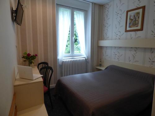 a bedroom with a bed and a desk with a laptop at Hôtel Saint Jean in Vals-les-Bains