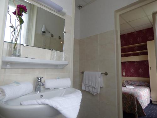 a bathroom with a sink and a mirror and a bed at Hôtel Saint Jean in Vals-les-Bains