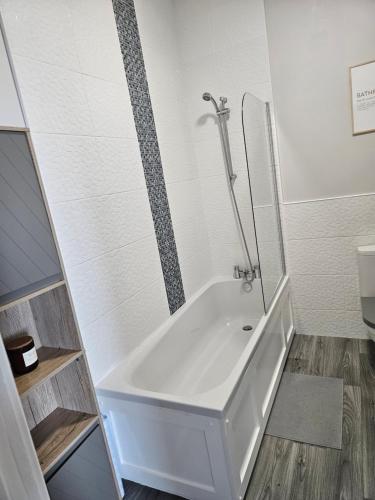 a white bath tub in a bathroom with a shower at Saltwater Edge Apartment in Portrush