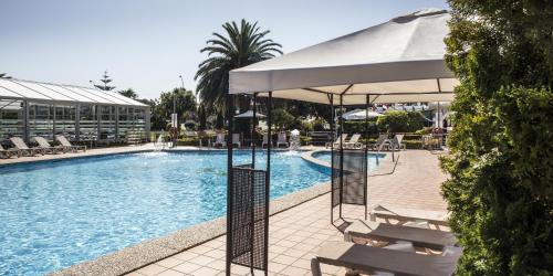 a large swimming pool with chairs and an umbrella at Nuevo Astur Spa in Sanxenxo