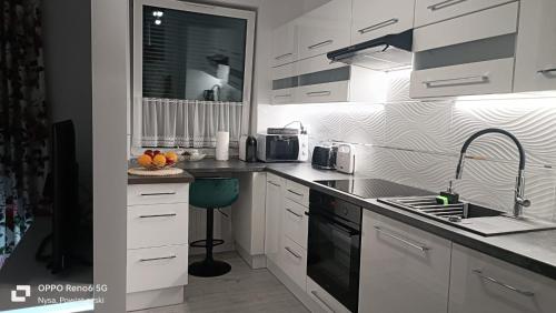 a white kitchen with a sink and a stove at BELWEDER in Nysa