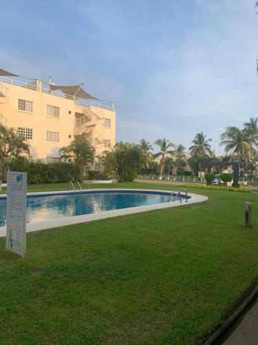 une piscine en face d'un grand bâtiment dans l'établissement Depto con PISCINA PUENTE DEL MAR ACAPULCO, à Acapulco