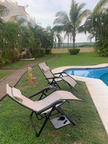 two lounge chairs sitting next to a swimming pool at Depto con PISCINA PUENTE DEL MAR ACAPULCO in Acapulco