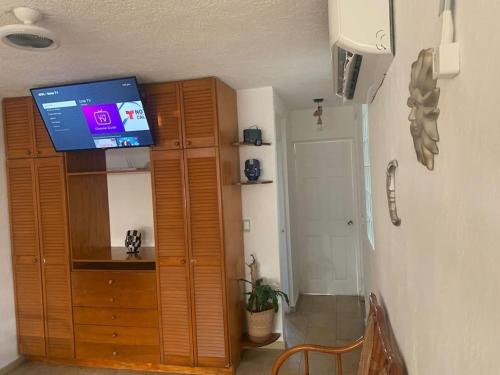 a room with a tv and a wooden cabinet at Depto con PISCINA PUENTE DEL MAR ACAPULCO in Acapulco