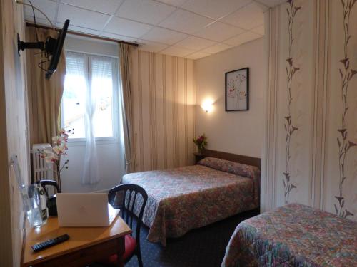a hotel room with two beds and a desk with a laptop at Hôtel Saint Jean in Vals-les-Bains