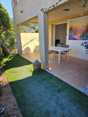 d'une terrasse avec une table et une pelouse. dans l'établissement Appartement 2 chambres, à Cavalaire-sur-Mer