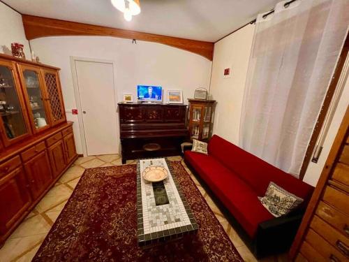 ein Wohnzimmer mit einem roten Sofa und einem Tisch in der Unterkunft La casa dell’artista di Vittorio Vertone in Pietragalla