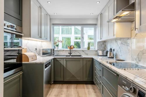 a kitchen with gray cabinets and a sink at Waterside Cottage - Hot Tub, Mooring, Arcade, Bar in Neatishead