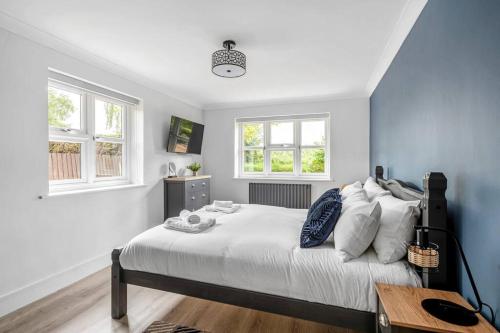 a bedroom with a large bed and two windows at Waterside Cottage - Hot Tub, Mooring, Arcade, Bar in Neatishead