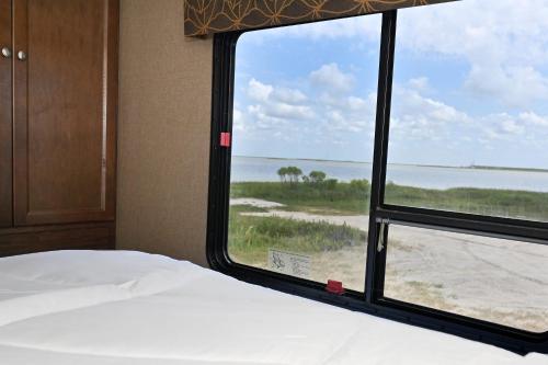 - une chambre avec une fenêtre donnant sur la plage dans l'établissement Bayside Glamping & Fishing, à Bolivar Peninsula