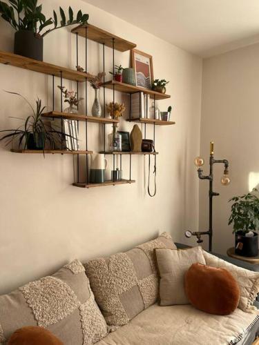 a living room with a couch and shelves with plants at Charmant appartement parisien, spacieux & lumineux in Paris