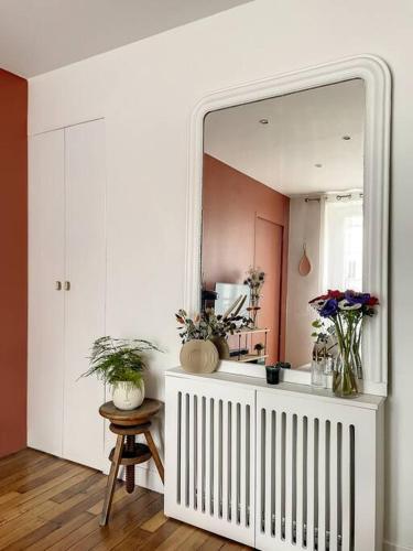 Cette chambre dispose d'un miroir et d'une table avec des plantes. dans l'établissement Charmant appartement parisien, spacieux & lumineux, à Paris